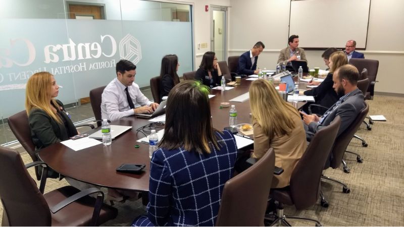 Students at conference room meeting, with Centra Care and Florida Hospital Urgent Care logos visible through glass wall