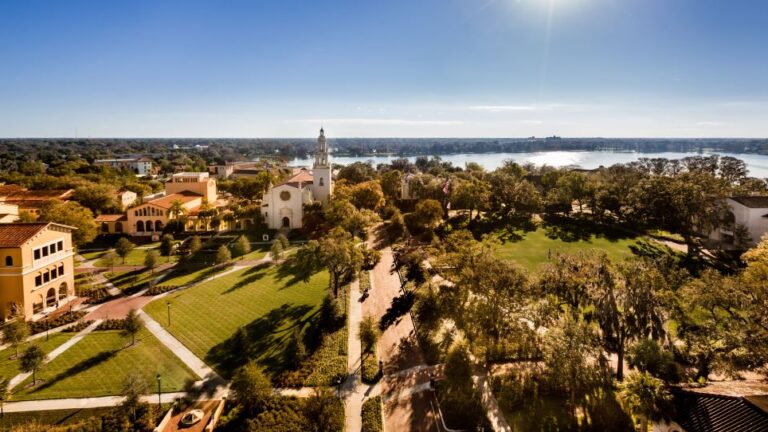 The Rollins College campus viewed from the top showcases a scenic lake, a chapel, and green space crossed by brick paths