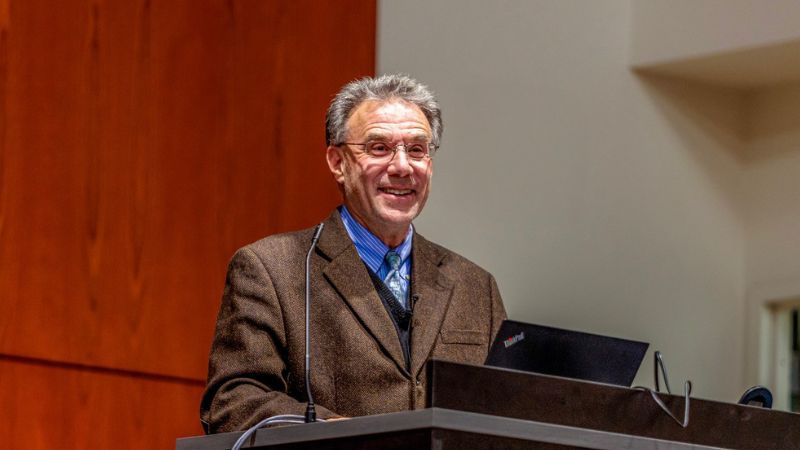 professor jay liebowitz standing behind a podium smiling at the audience