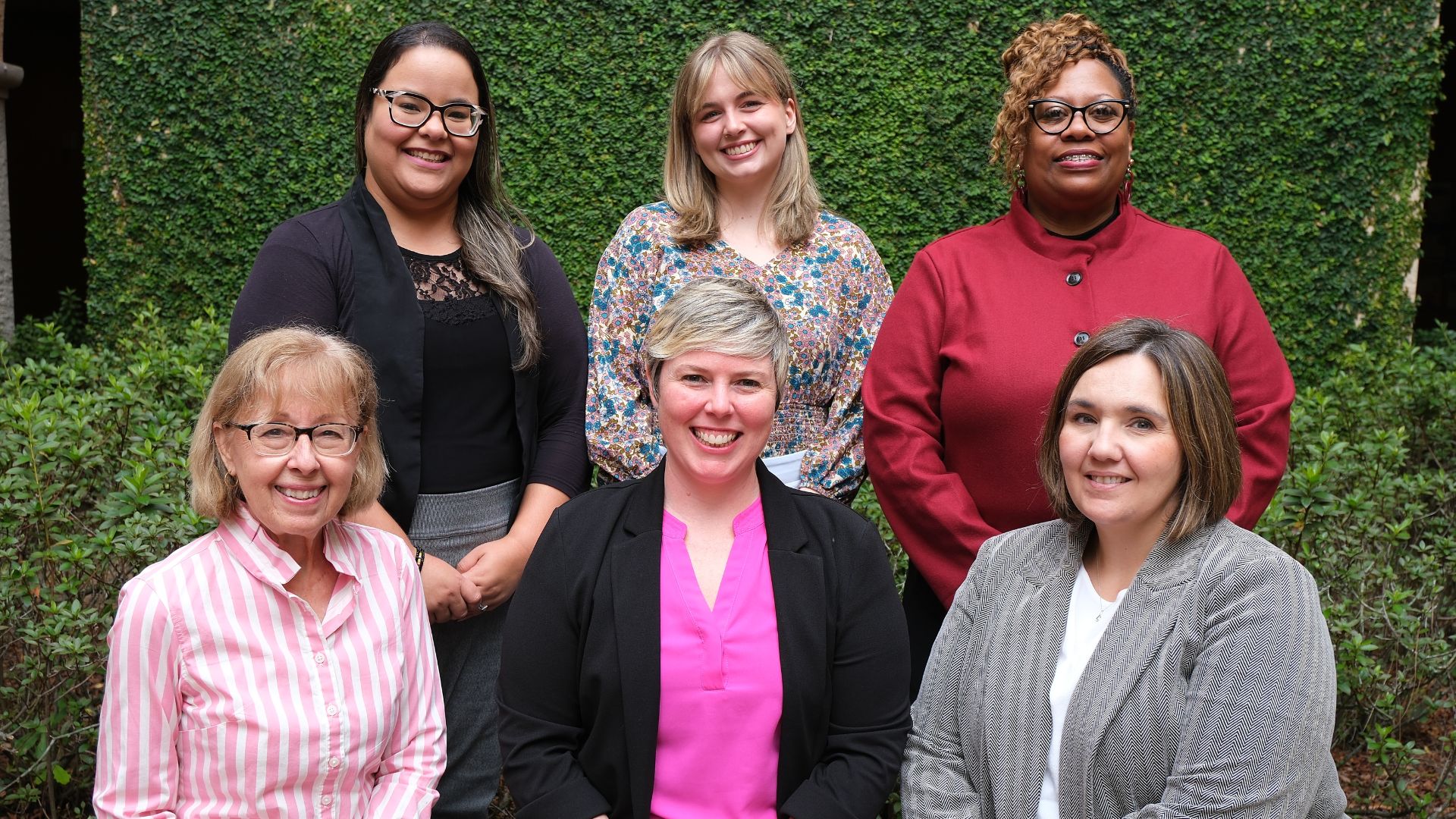 student success team posing together in front of vine-clad wall