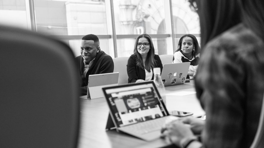 Group of professionals working on laptops in a meeting room (black and white).