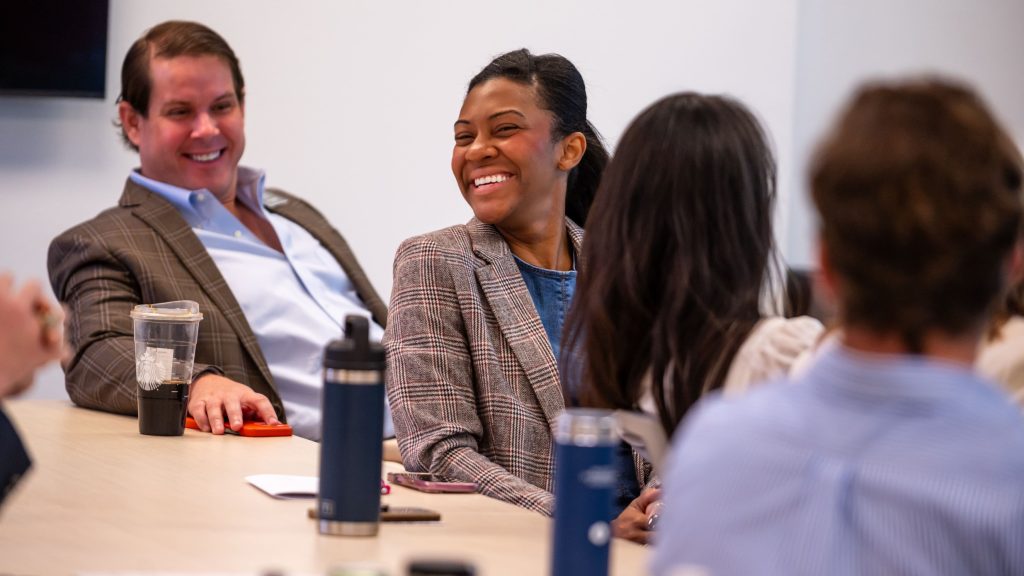 Two executive students smiling and laughing at a conference table.