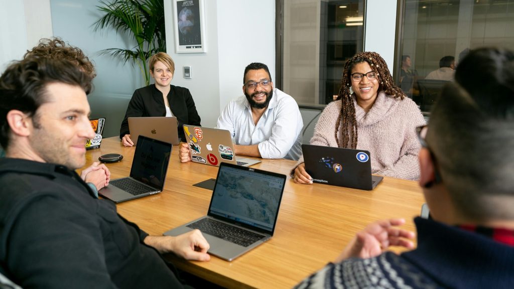 Team of professionals collaborating in a conference room with laptops.