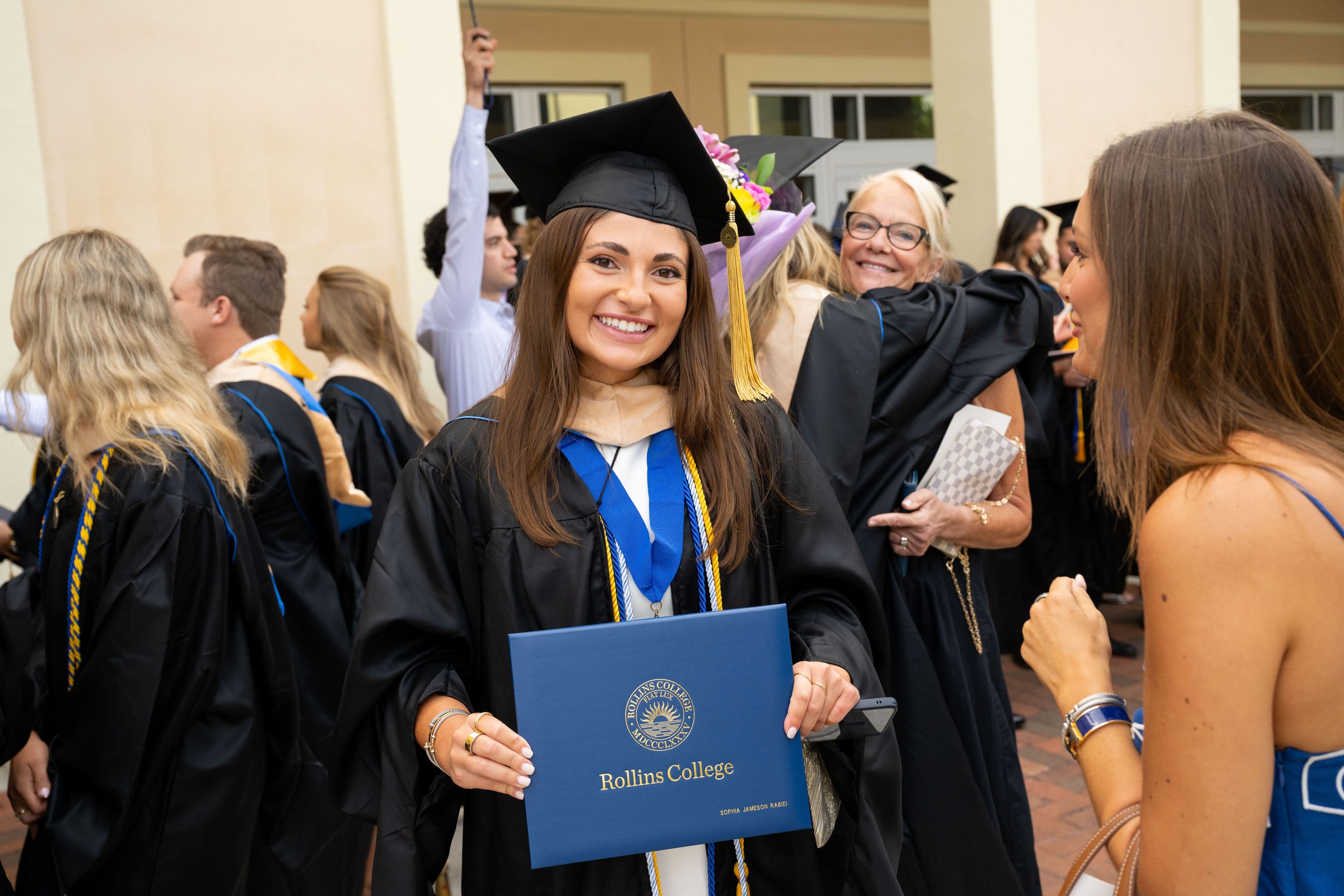 Smiling MBA graduate in a cap and gown holding her diploma.