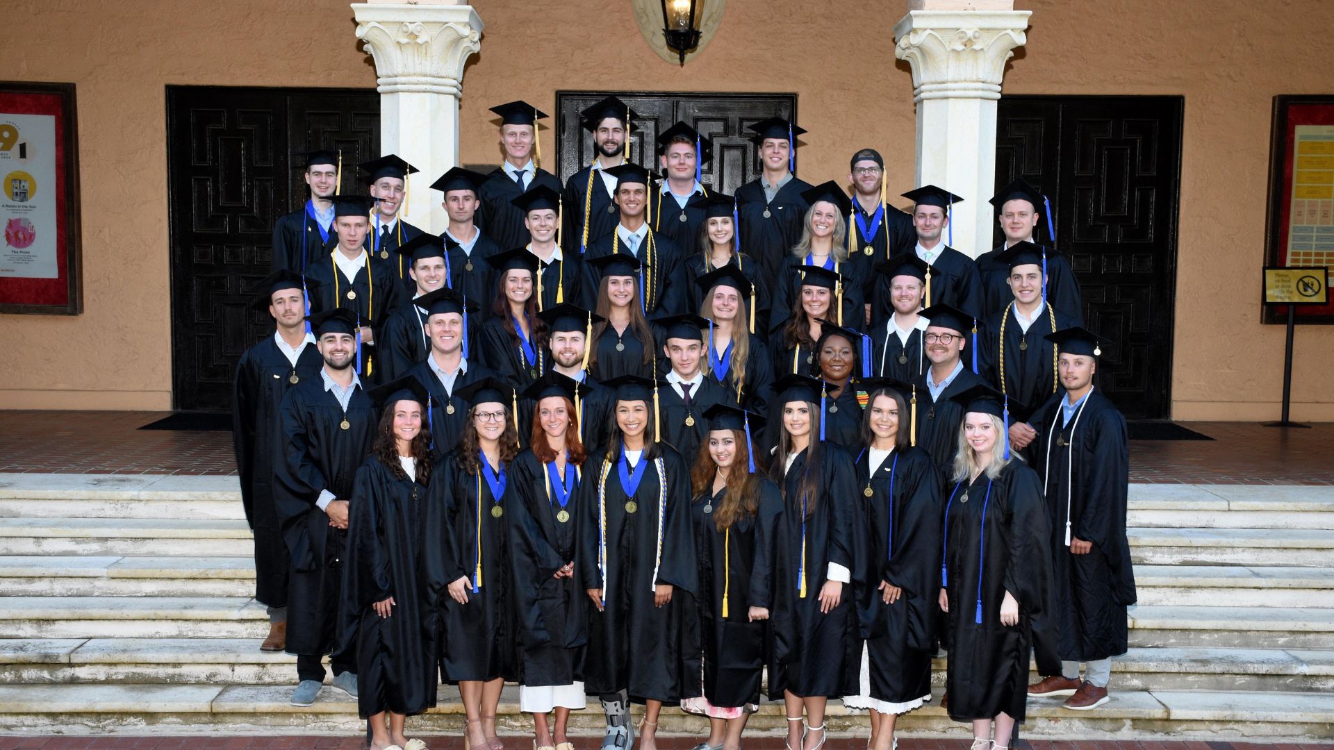 a large group of students stand together on a set of stairs in their cap and gowns